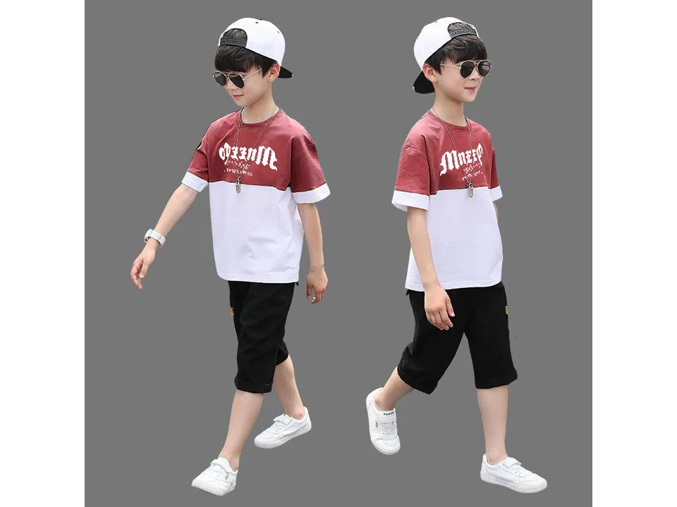 A boy wearing a red and white color-blocked t-shirt and black shorts.