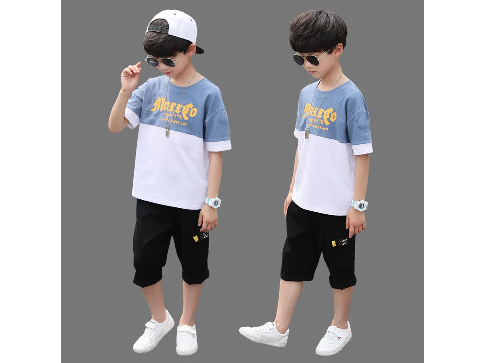 A boy wearing a blue and white color-blocked t-shirt and black shorts.