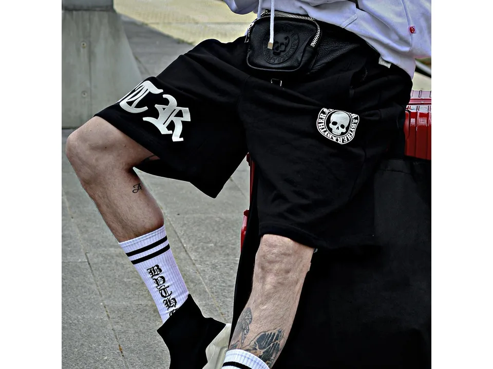Close-up of a person wearing black graphic sweatshorts.