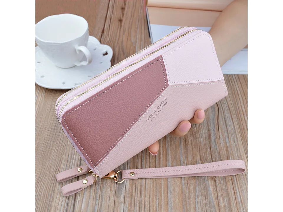 Two-tone pink long wallet with wrist strap held in hand