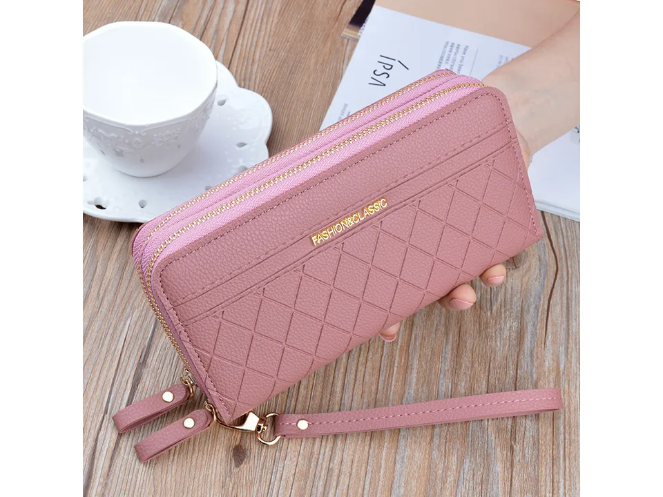 Pink quilted long wallet with wrist strap held in hand
