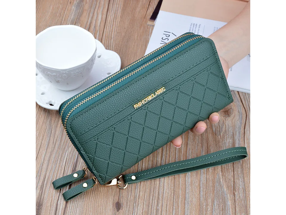 Green quilted long wallet with wrist strap held in hand