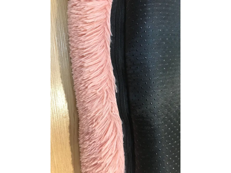 Close-up of the pink plush fabric and the black zipper on the pet bed.