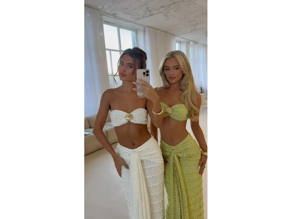Two women posing together, one wearing a white lace two-piece set and the other a lime green one.