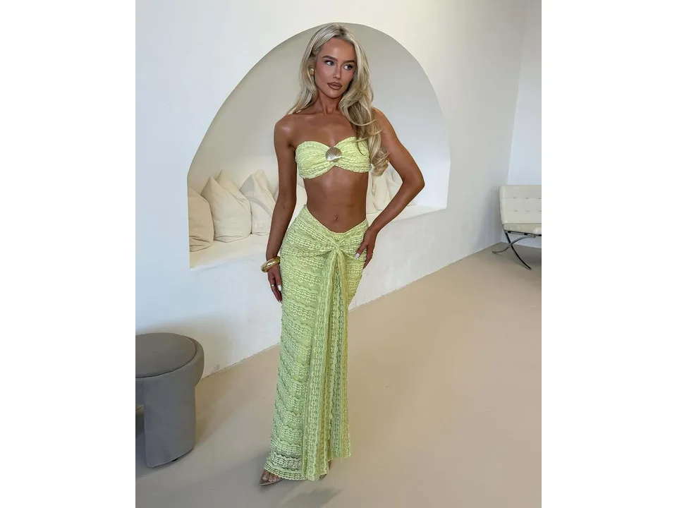 A woman wearing a lime green lace two-piece set with a tube top and long skirt.