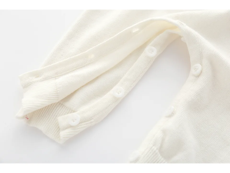 Close-up of the white button closure on the leg of the knitted jumpsuit.
