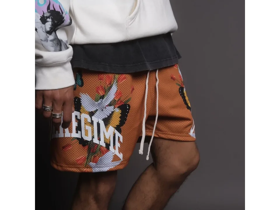 Close-up of orange athletic shorts with graphic print on a person.