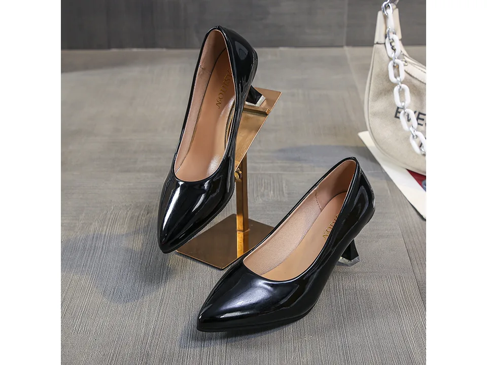 A pair of black pointed toe stiletto pumps on a display stand.