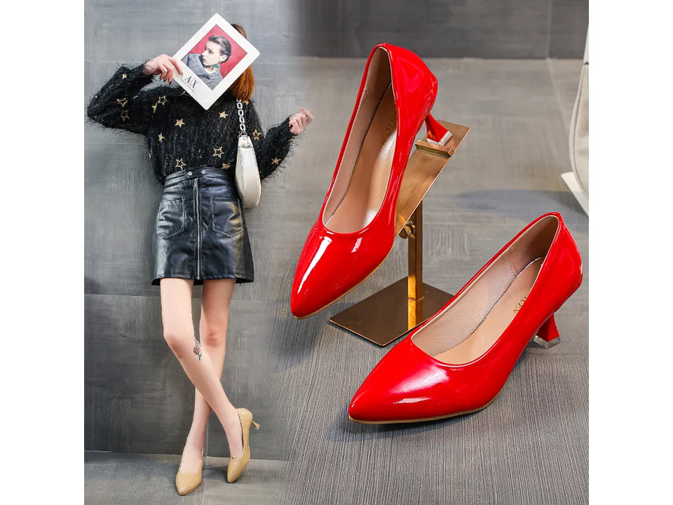 A woman wearing beige pointed toe stiletto pumps with a black skirt.