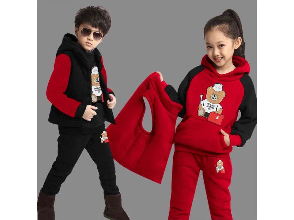 A boy and a girl wearing a red and black hooded sweatshirt and pants set with a bear graphic.