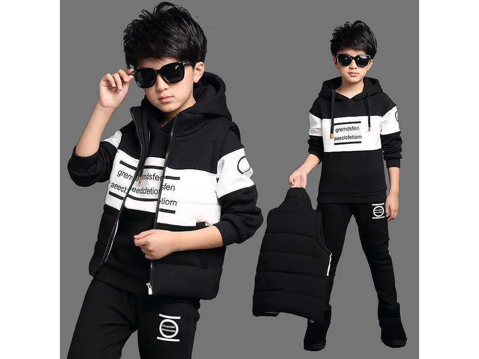 A boy wearing a black and white hooded sweatshirt and pants set with a vest.