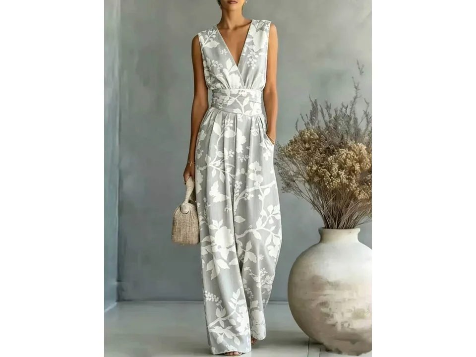 A woman wearing a sleeveless V-neck wide-leg jumpsuit with a grey and white floral pattern.