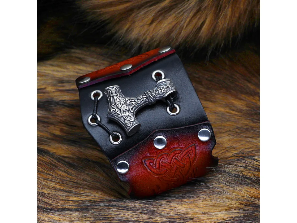 Close-up of a leather Viking bracelet with a silver-toned Thor's hammer pendant.