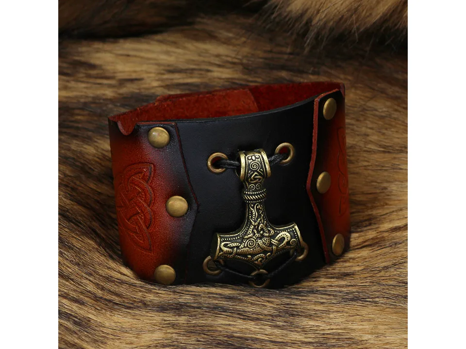 Close-up of a leather Viking bracelet with a gold-toned Thor's hammer pendant.