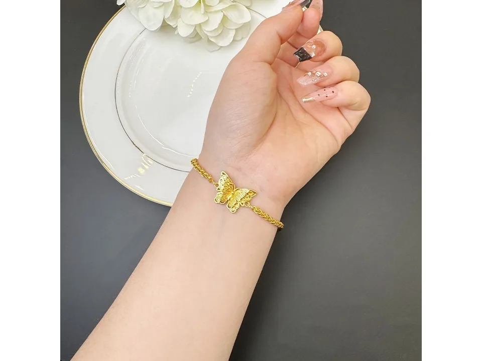 A gold-plated butterfly bracelet worn on a person's wrist.