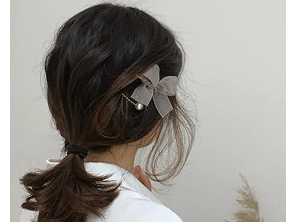 A woman wearing the grey bow and pearl hair clip in her hair.