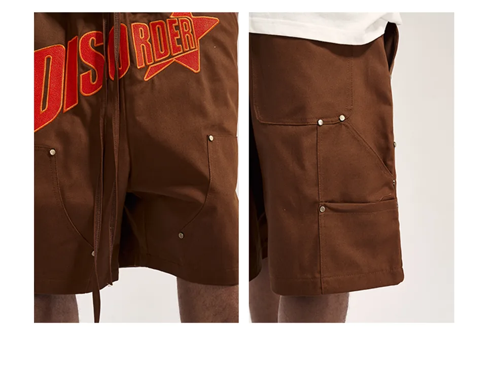 Close-up of the embroidered 'DISORDER' logo and side pocket details on brown shorts.
