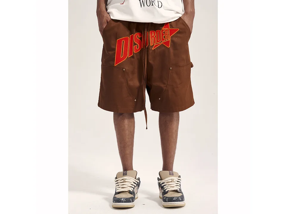 Front view of brown cargo shorts with 'DISORDER' embroidery on a person.