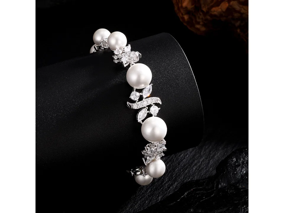 Close-up of a pearl and zircon bracelet on a black display stand.