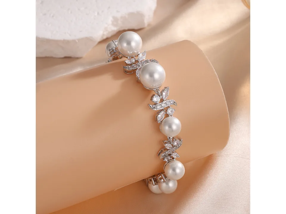 A pearl and zircon bracelet wrapped around a beige display cylinder.
