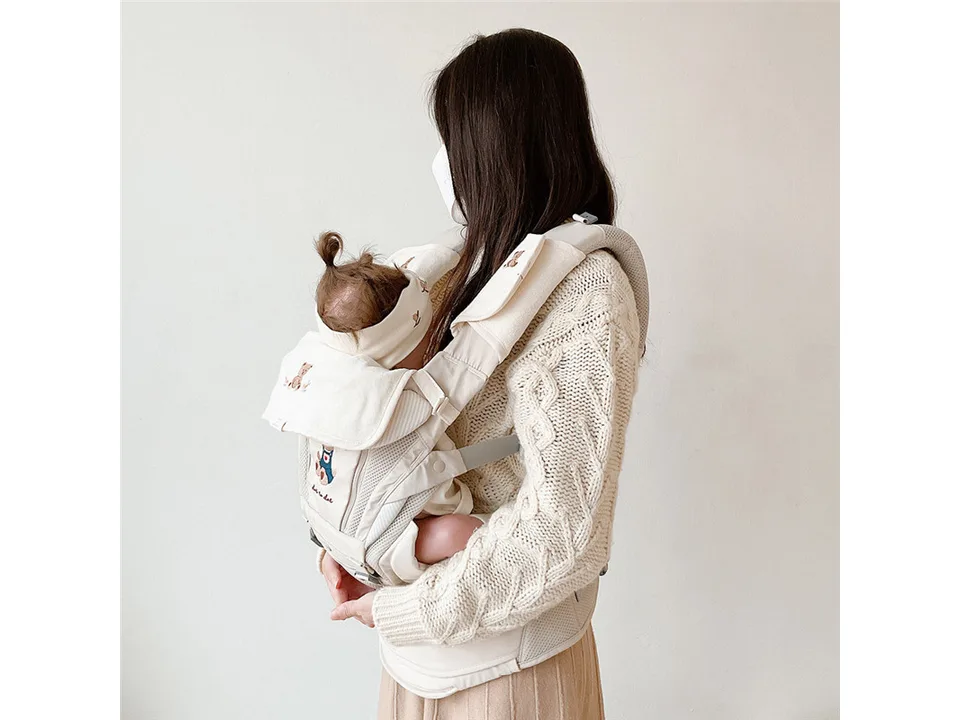 A person wearing a baby carrier with the protective shoulder and chest covers attached.