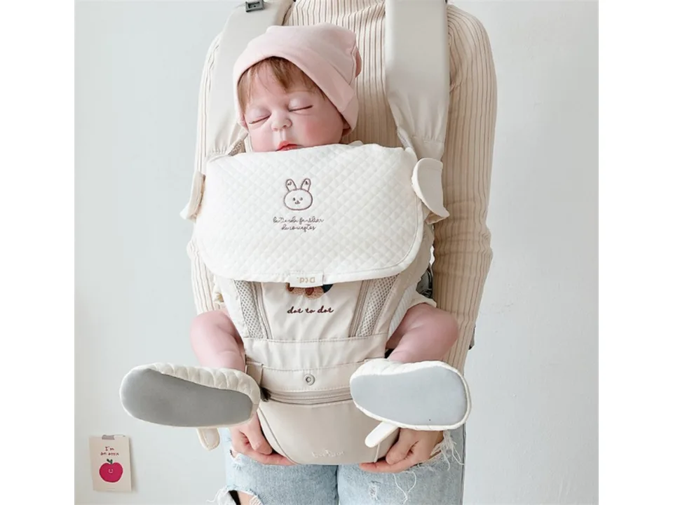 A person carrying a baby in a carrier with the protective chest cover clearly visible.