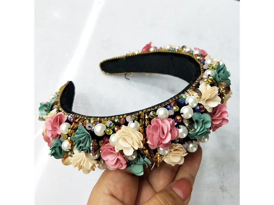 Close-up of a bridal headband decorated with fabric flowers, pearls, and crystals.