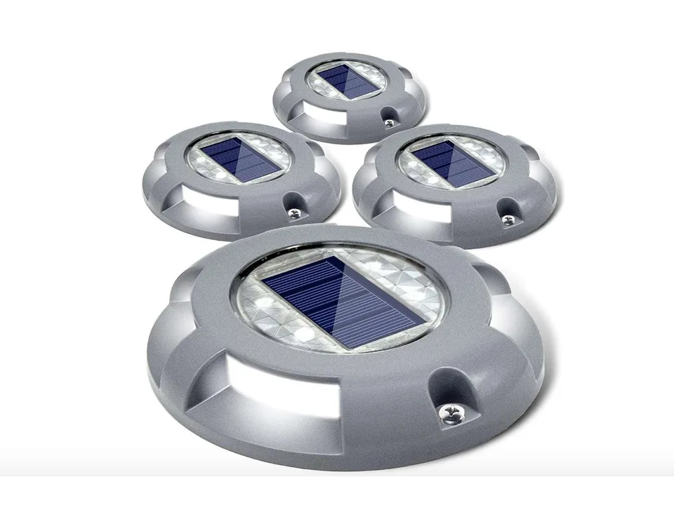 Four solar-powered ground lights arranged on a white background.