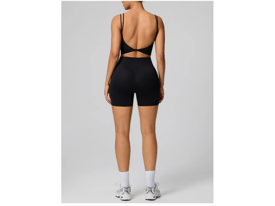 Back view of a model wearing a black twist backless tank top and matching shorts.