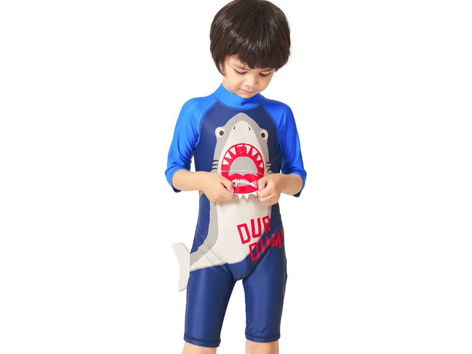 A close-up of a boy opening the shark mouth detail on the front of the swimsuit.