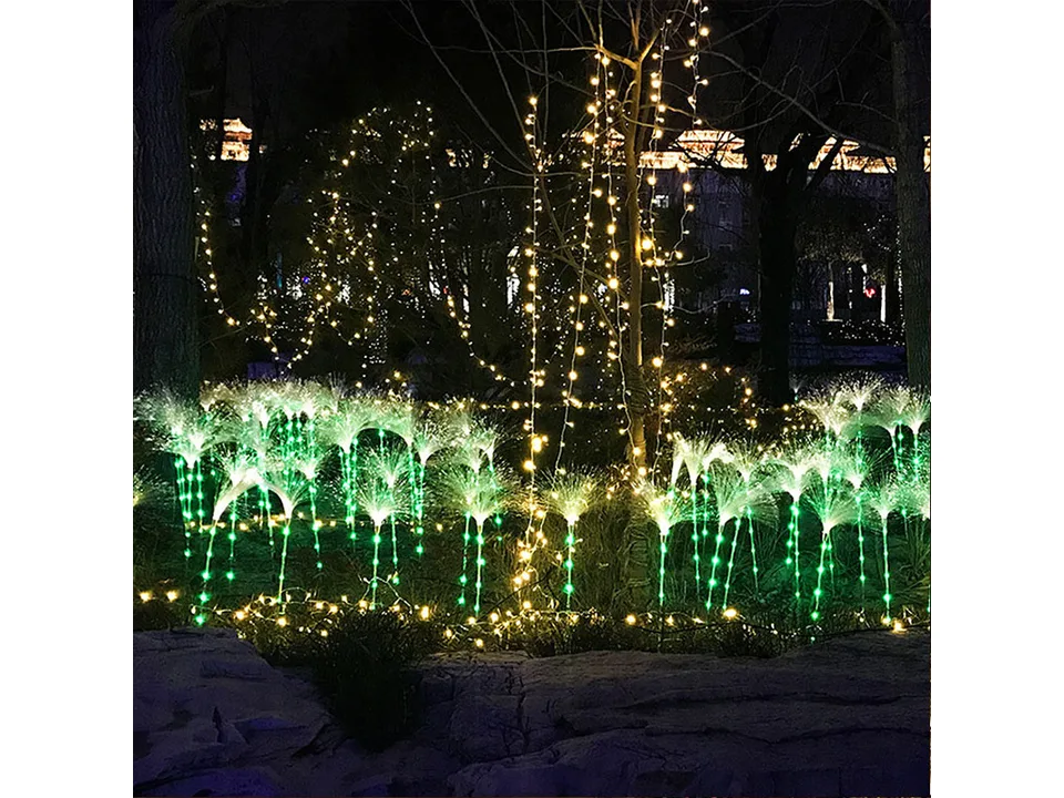 Multiple fiber optic landscape lights glowing green in a garden at night.
