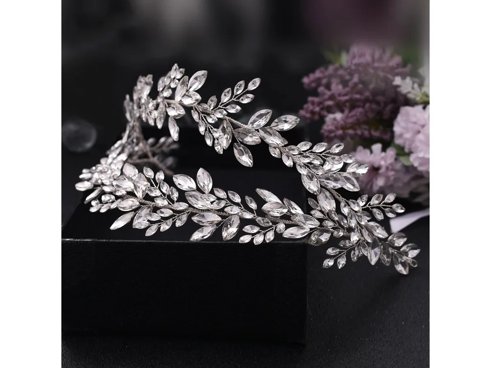 A silver rhinestone bridal hairband with leaf designs resting on a black box.