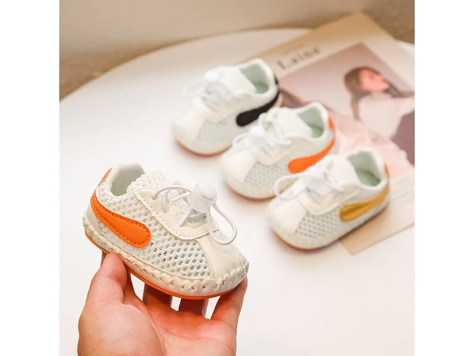 Three pairs of baby sneakers in different colors being held.
