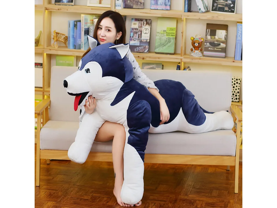 A woman lying on a sofa with a large husky plush toy.