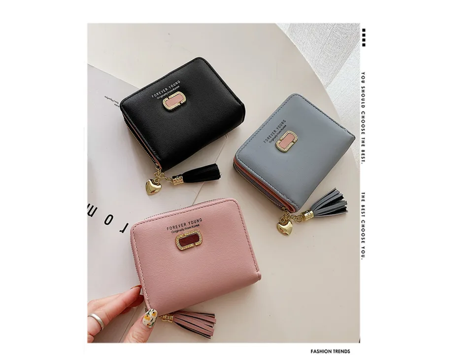 Three small wallets in black, grey, and pink displayed on a table.