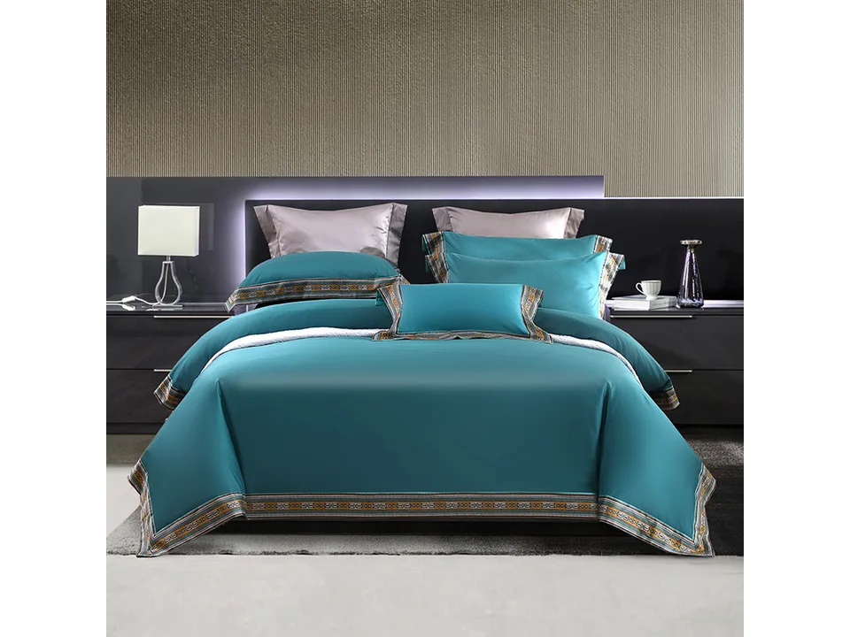 Teal bedding set with decorative patterned edges on a bed in a modern bedroom.
