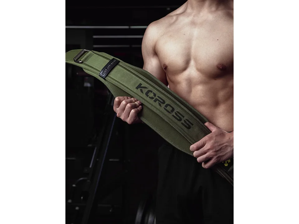 A man holding a green weightlifting belt, showing the KCROSS logo.