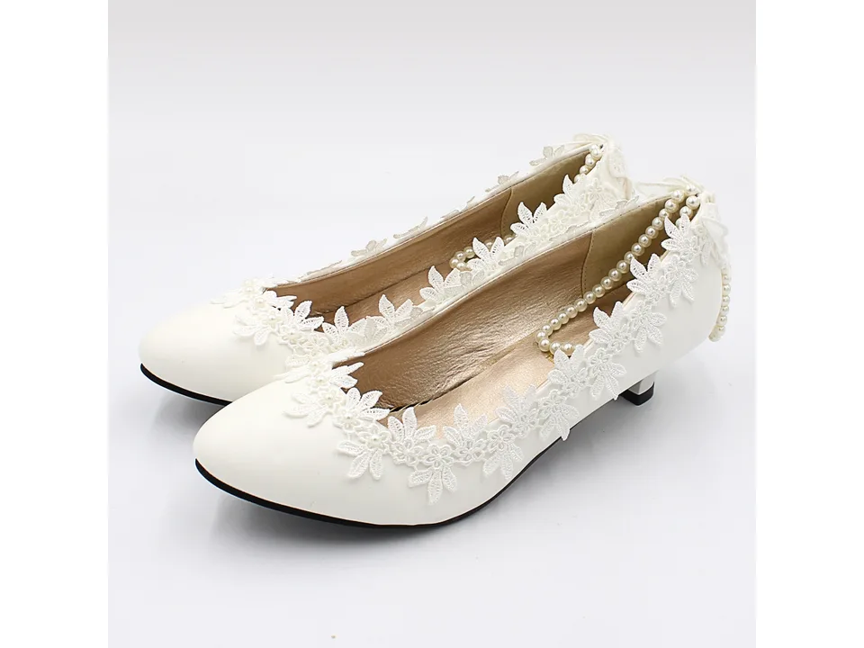 Side view of white lace wedding pumps with pearl details.