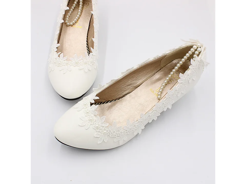 Top view of white lace wedding pumps with pearl embellishments.