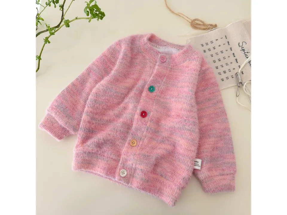 A pink knit cardigan with multi-colored buttons laid flat.