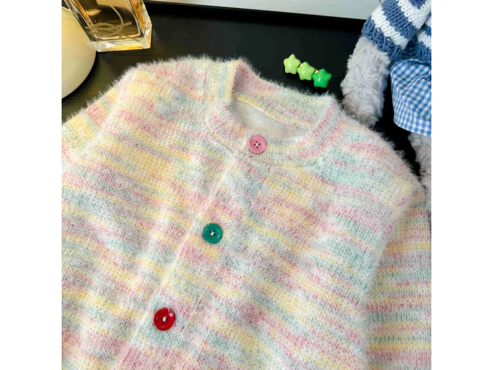Close-up of the knit texture and colorful buttons on the cardigan.
