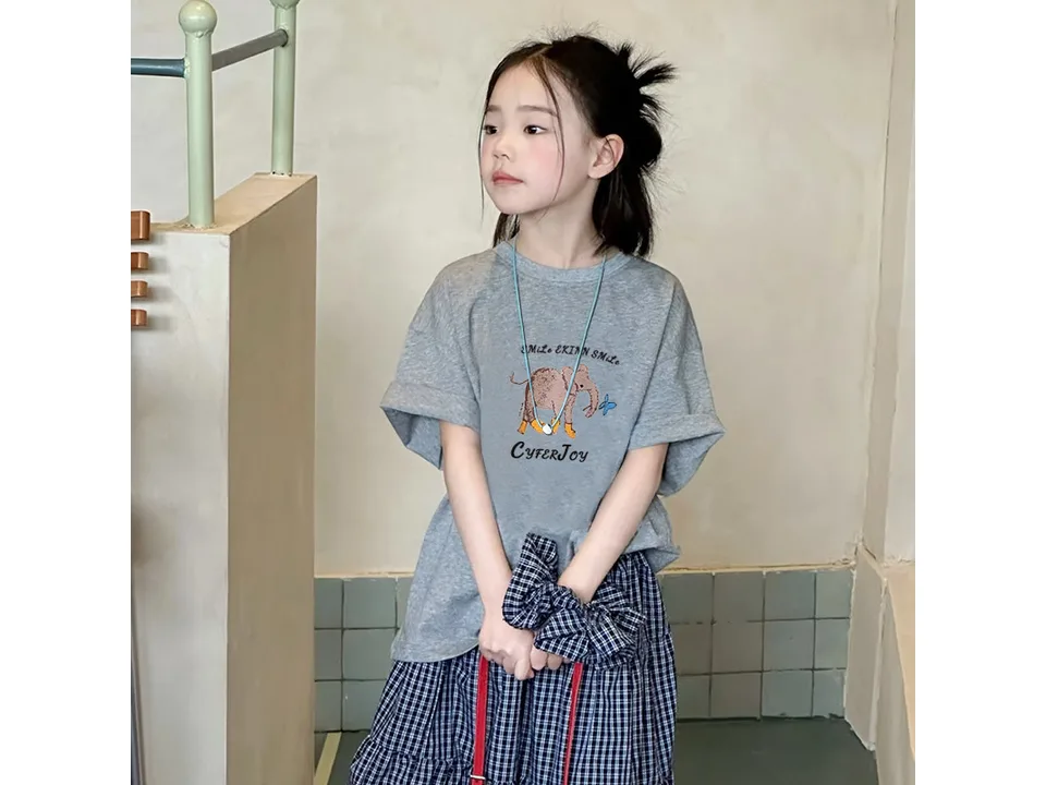A young girl wearing a grey short-sleeved t-shirt with an elephant graphic.
