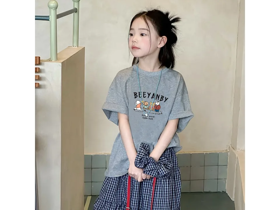 A young girl wearing a grey short-sleeved t-shirt with a cartoon animal group graphic.