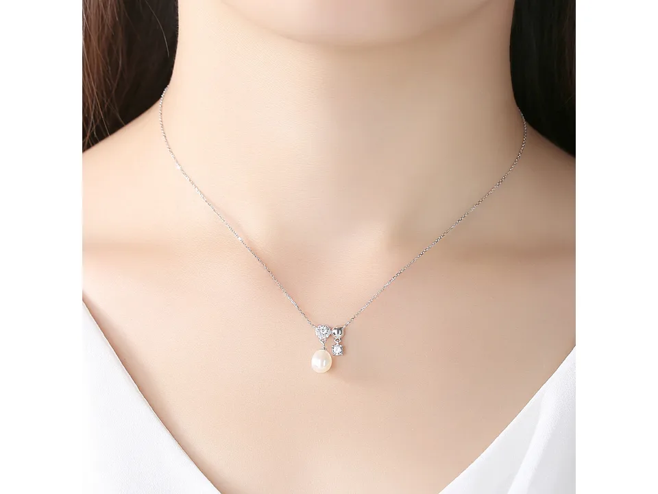 The pearl pendant necklace worn on a person's neck.