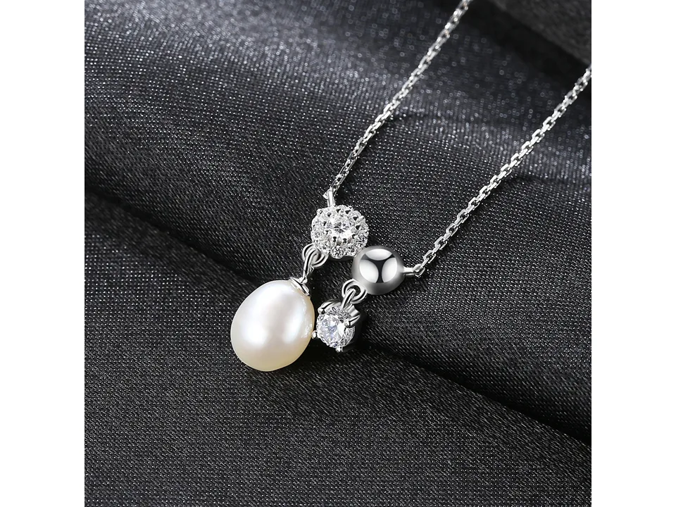 Close-up of the pearl and crystal pendant on a black background.