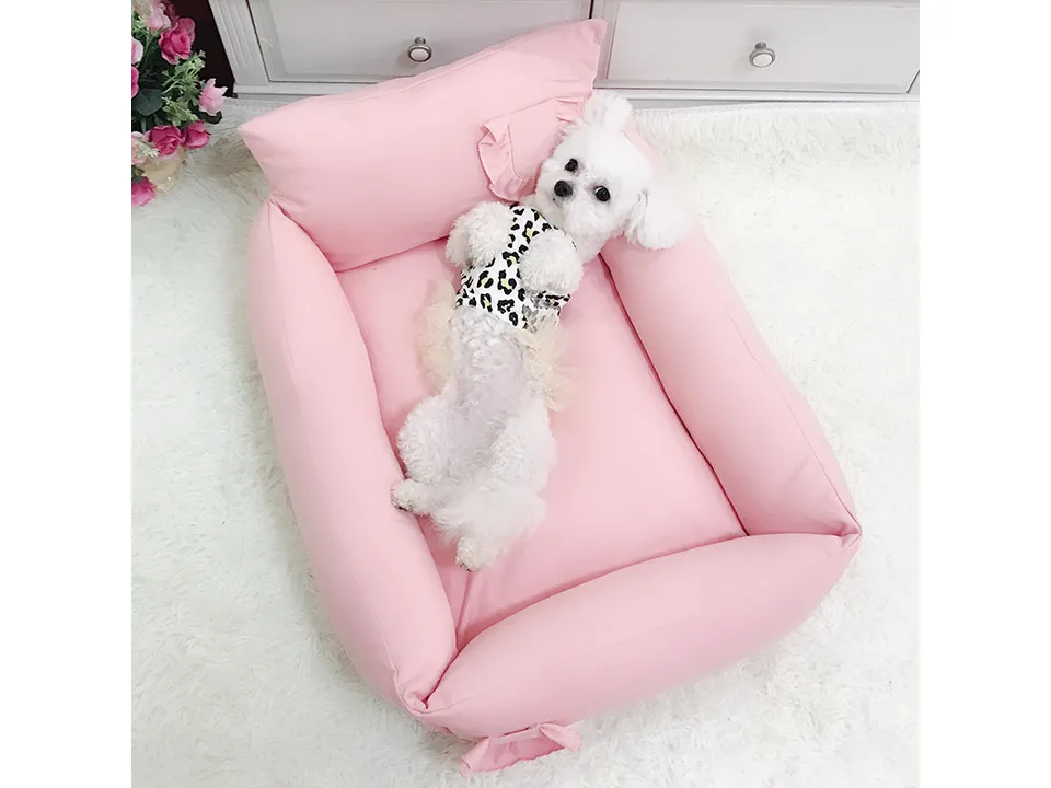 Small white dog lying in a pink pet bed.