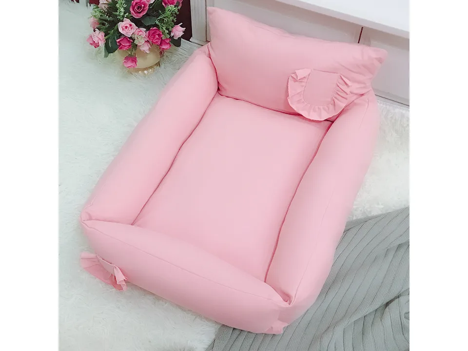 Pink pet bed on a white rug with flowers in the background.