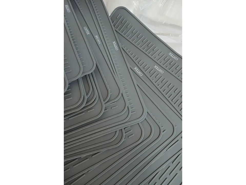 A stack of grey silicone mats showing the textured surface and brand logo.