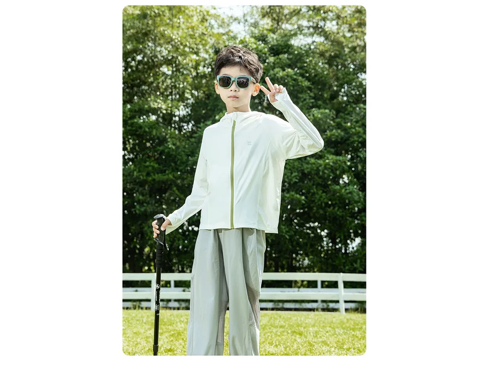 A young boy wearing a white UV protection hoodie jacket outdoors.
