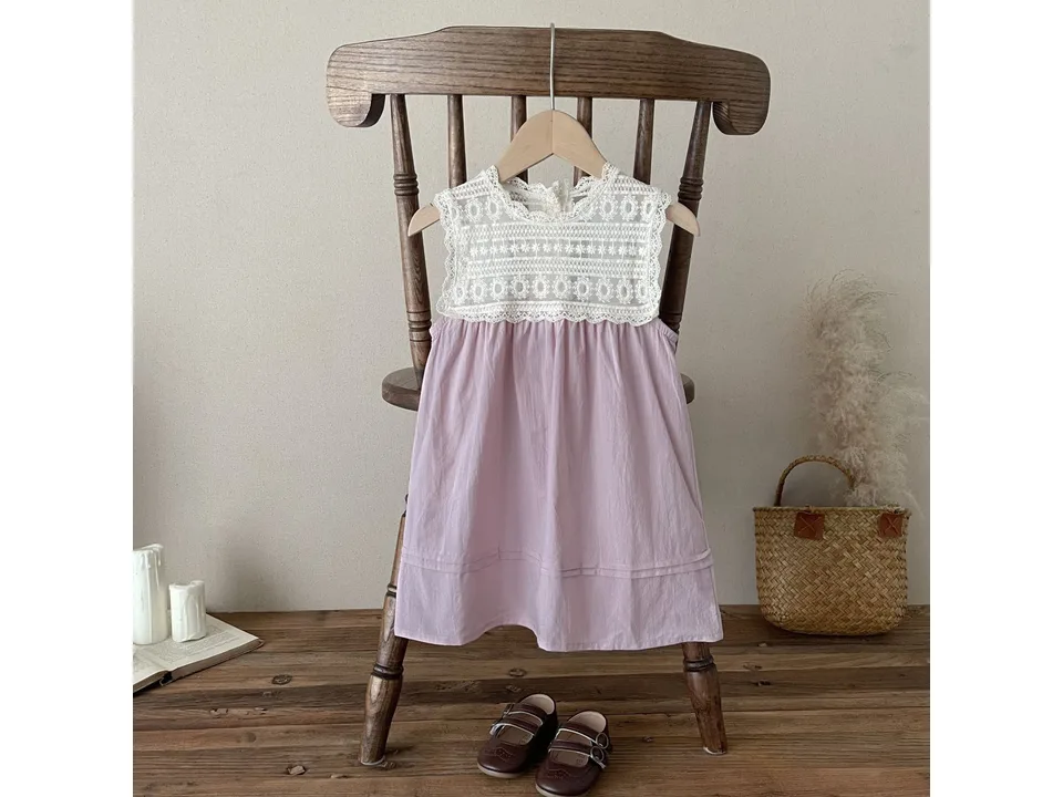 Pink baby dress with lace bodice hanging on a wooden chair